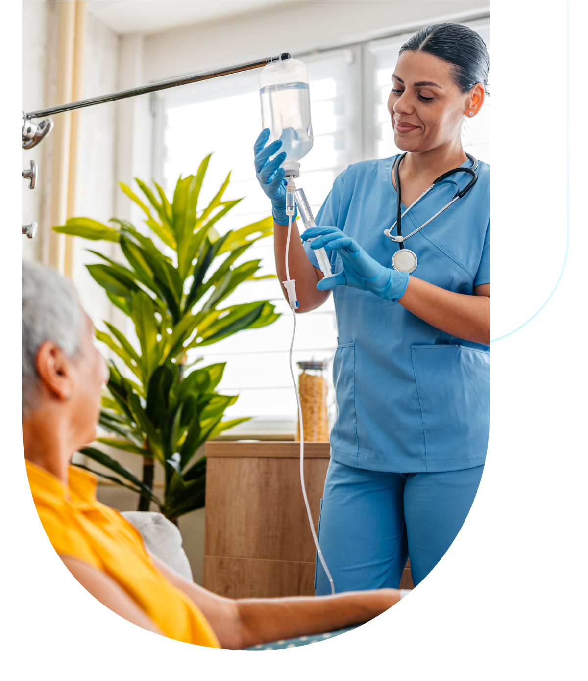 Woman receives a home infusion from a female nurse, there's a plant in the background