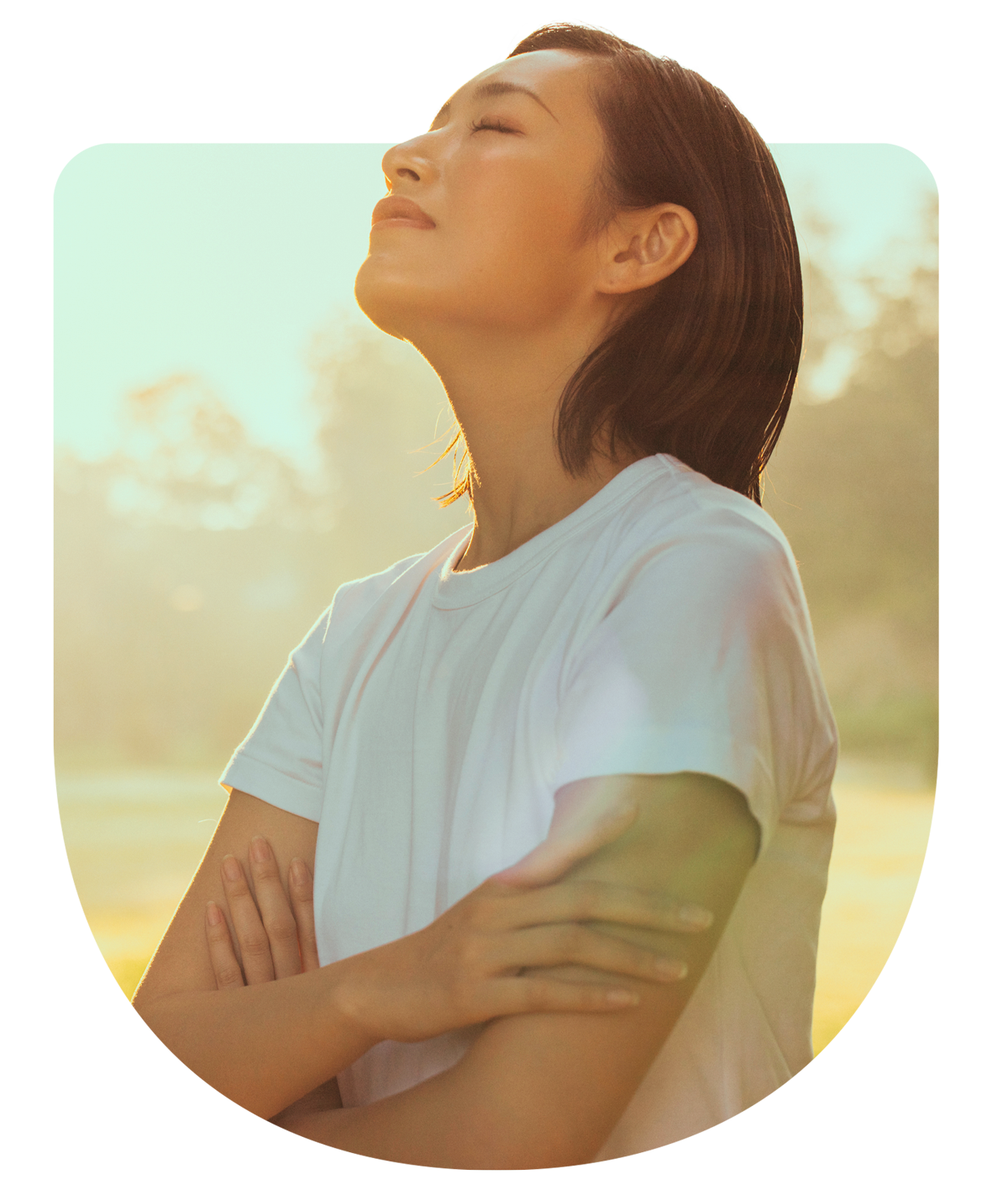 Woman of asian descent wearing a white t-shirt with her eyes closed basking in the light
