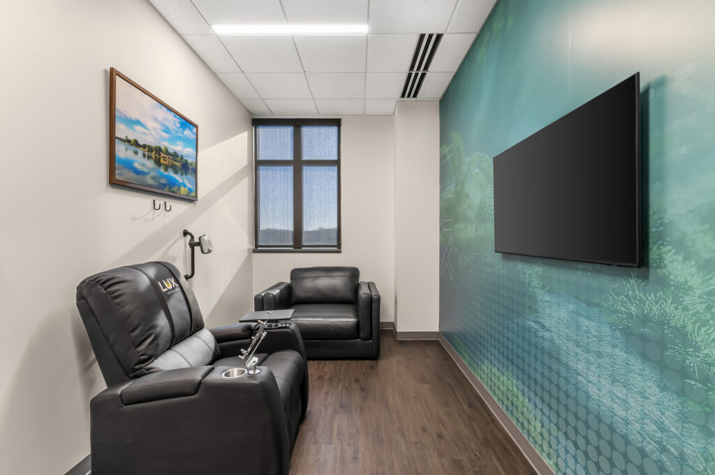 Solo infusion room, chair on the left, tv on the right, wall mural behind the tv