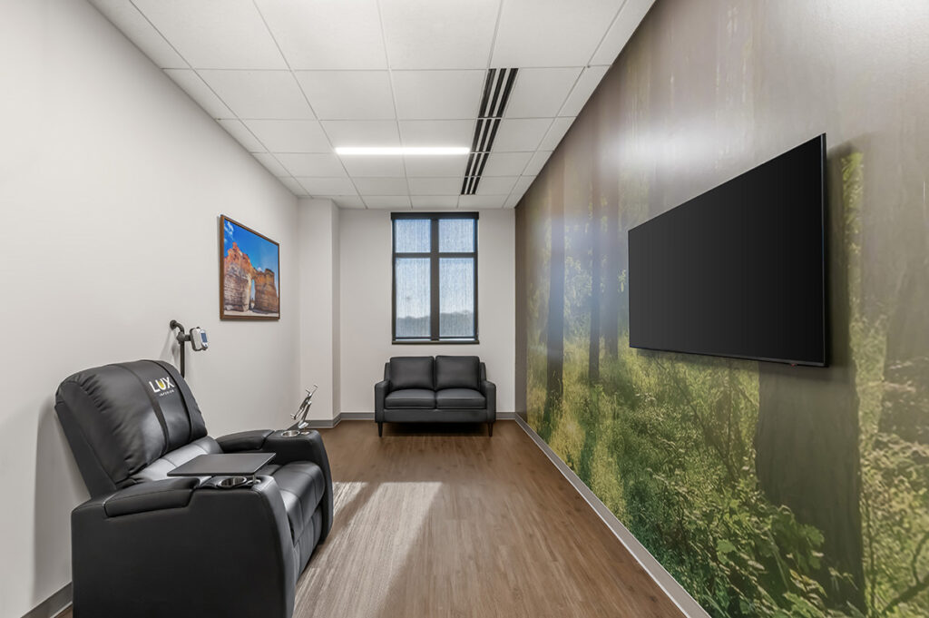 Solo infusion room, chair on the left, tv on the right, wall mural behind the tv